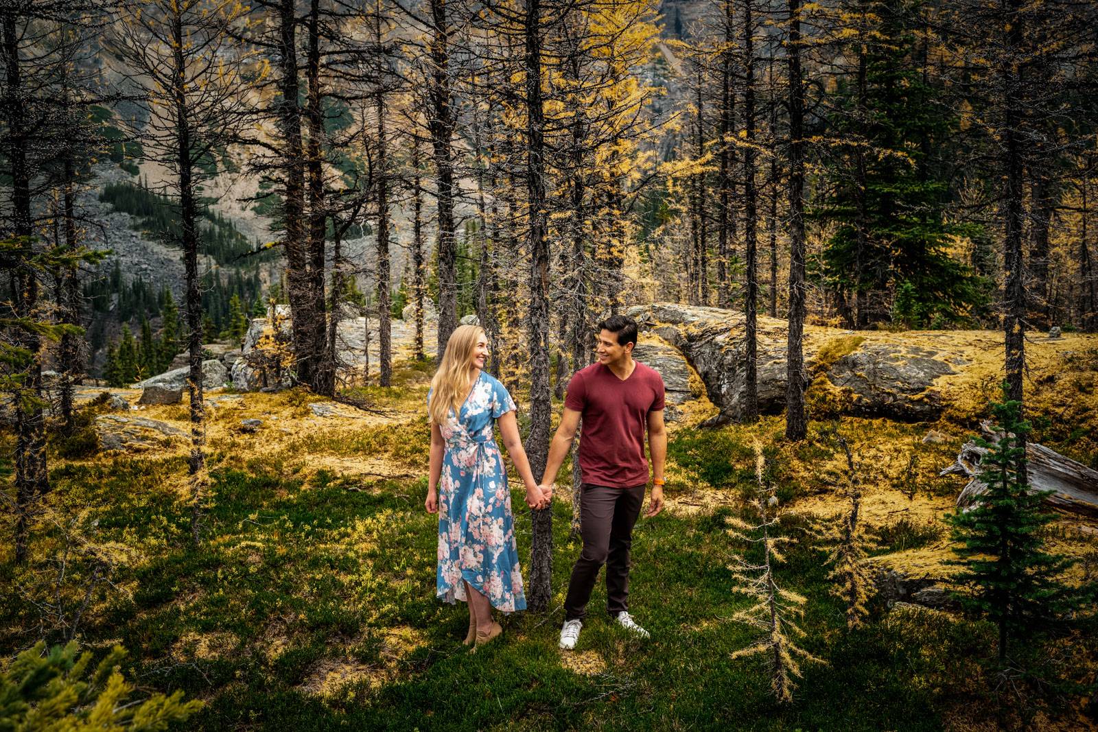 engaged couple hold their hands in the forest