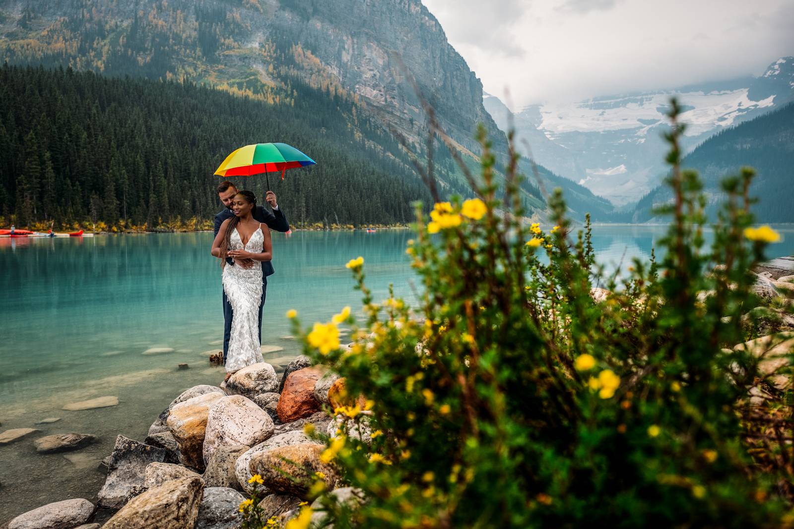 married couple holding colourful umbrella at Lake Louise
