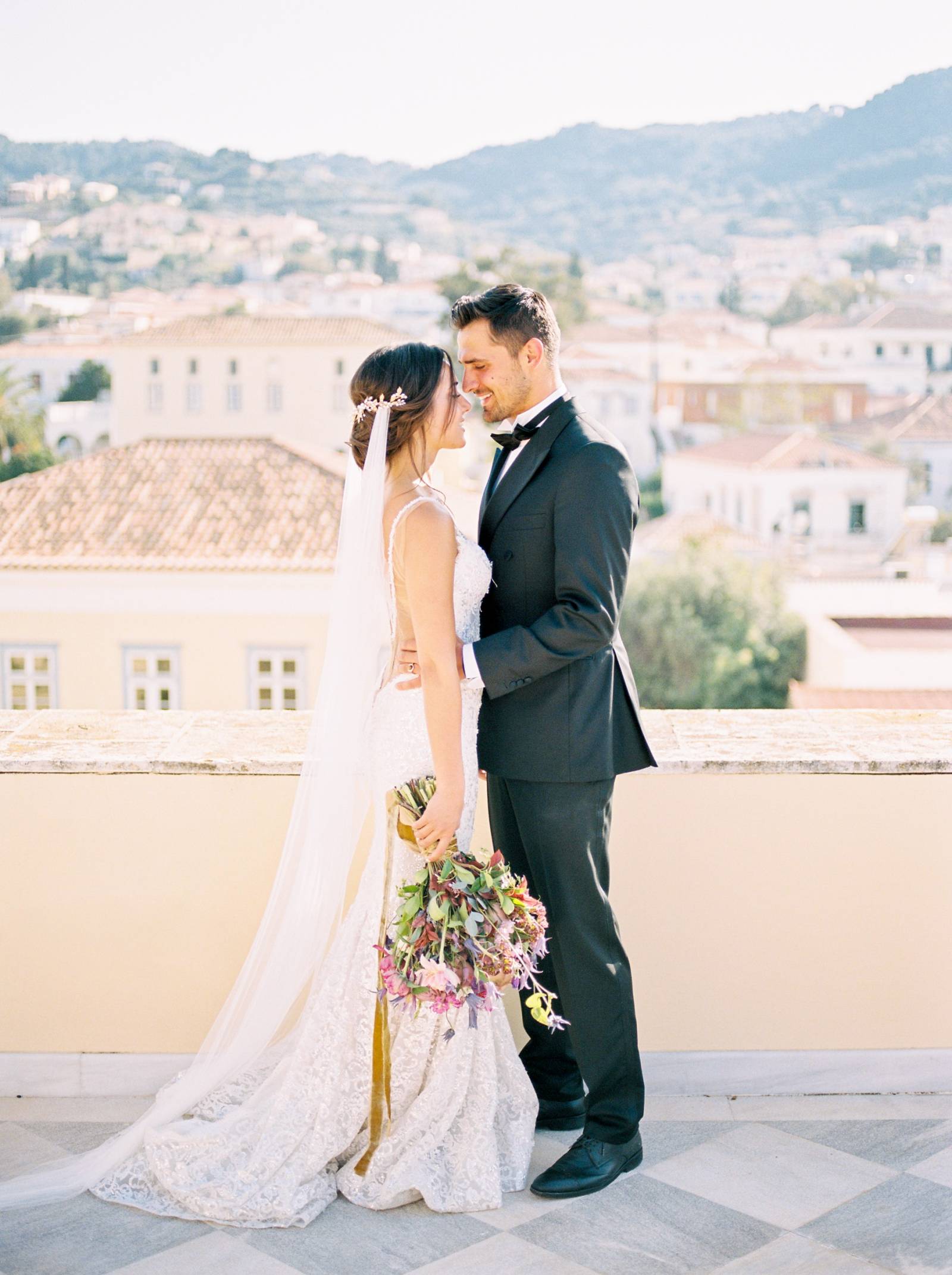 a bride and groom standing on the roof of the Poseidonion Hotel in Spetses Greece on their wedding d