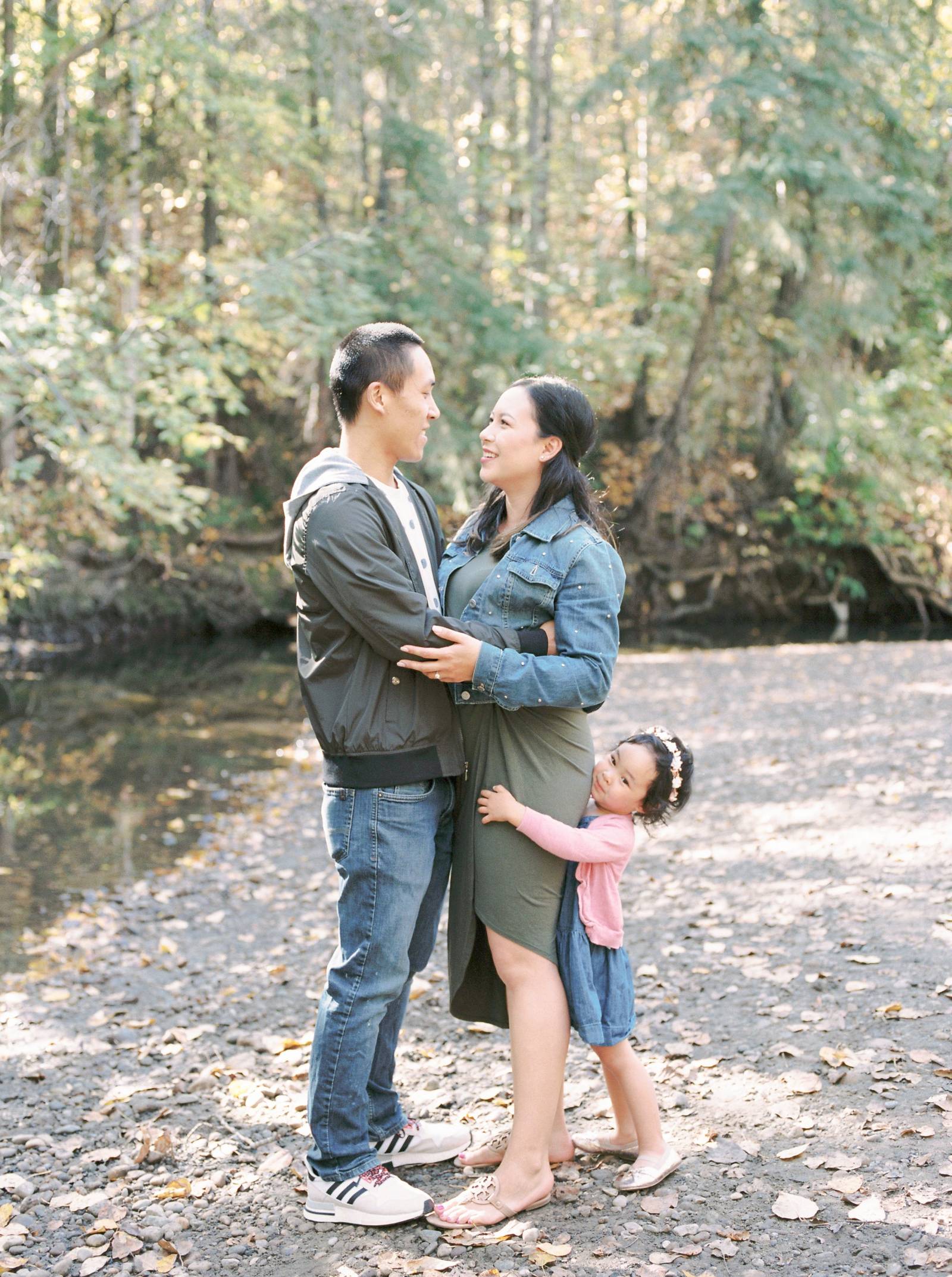 A young Asian family hug on the bank of a fall creek bed in Edmonton
