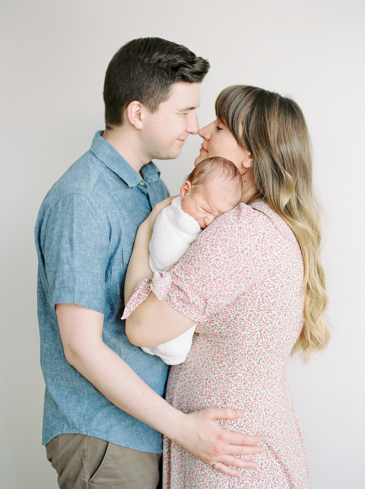 A newborn baby is cuddled by his mom and dad