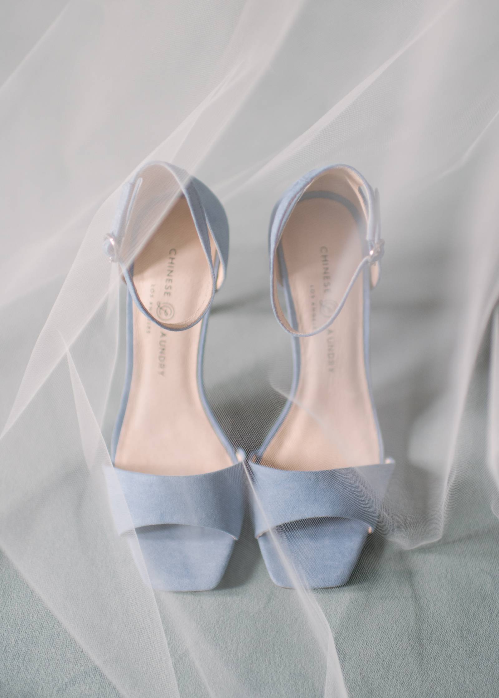 a brides shoes elegantly draped with her wedding veil