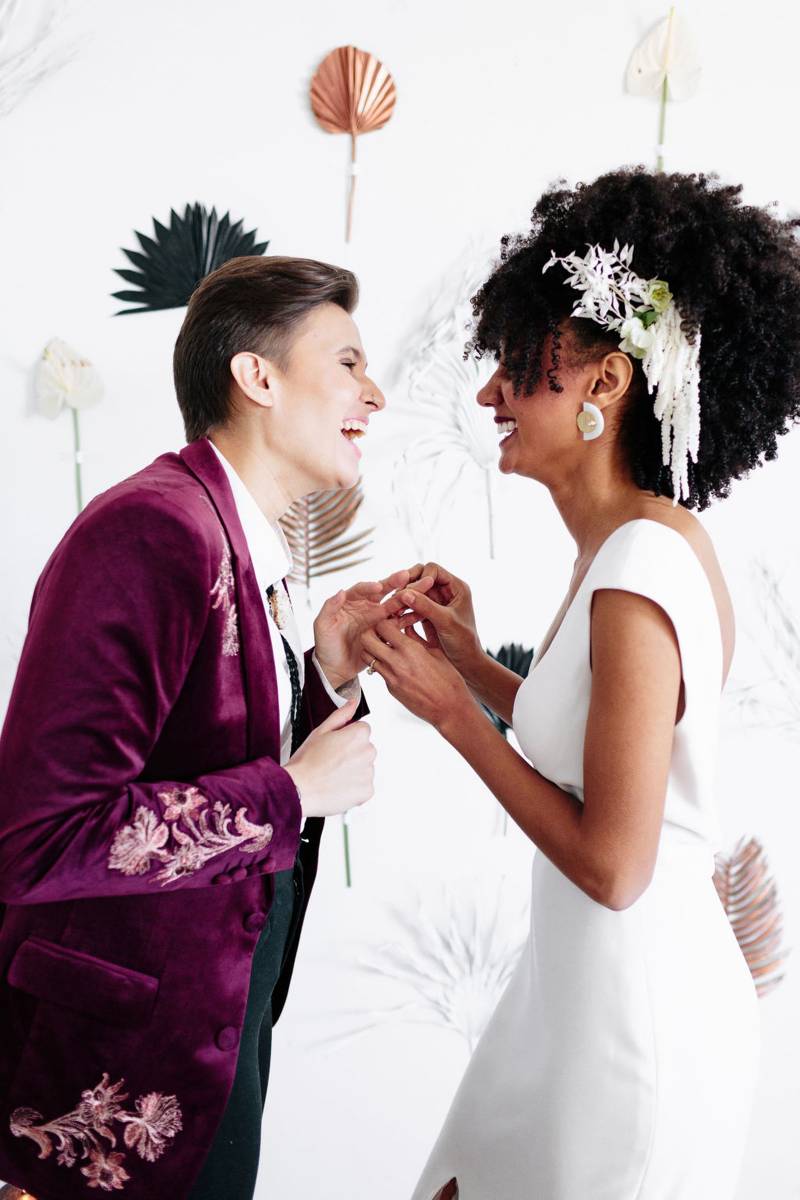 Brides laughing in front of modern floral backdrop