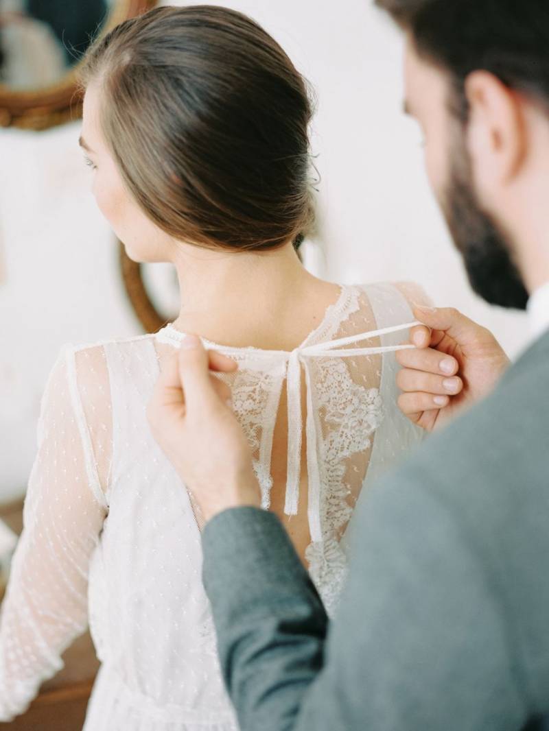 Groom tying bride's gown