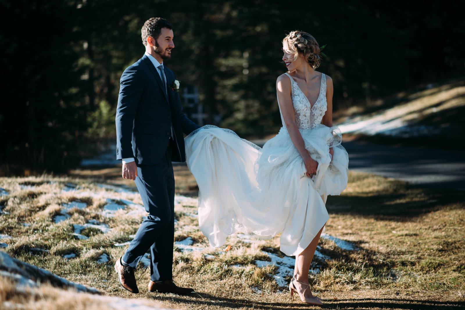 bride walking while groom carries her wedding dress train