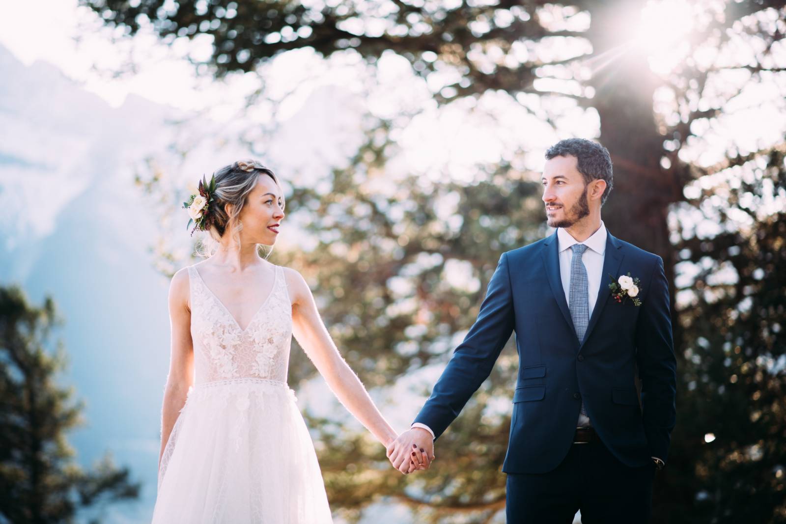 bride in deep v wedding dress holding hands with groom in Canmore