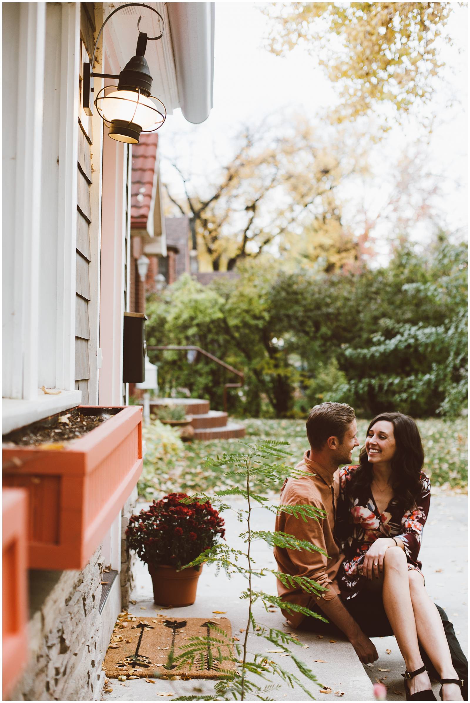 young couple snuggling up on home front porch | moody engagement inspiration