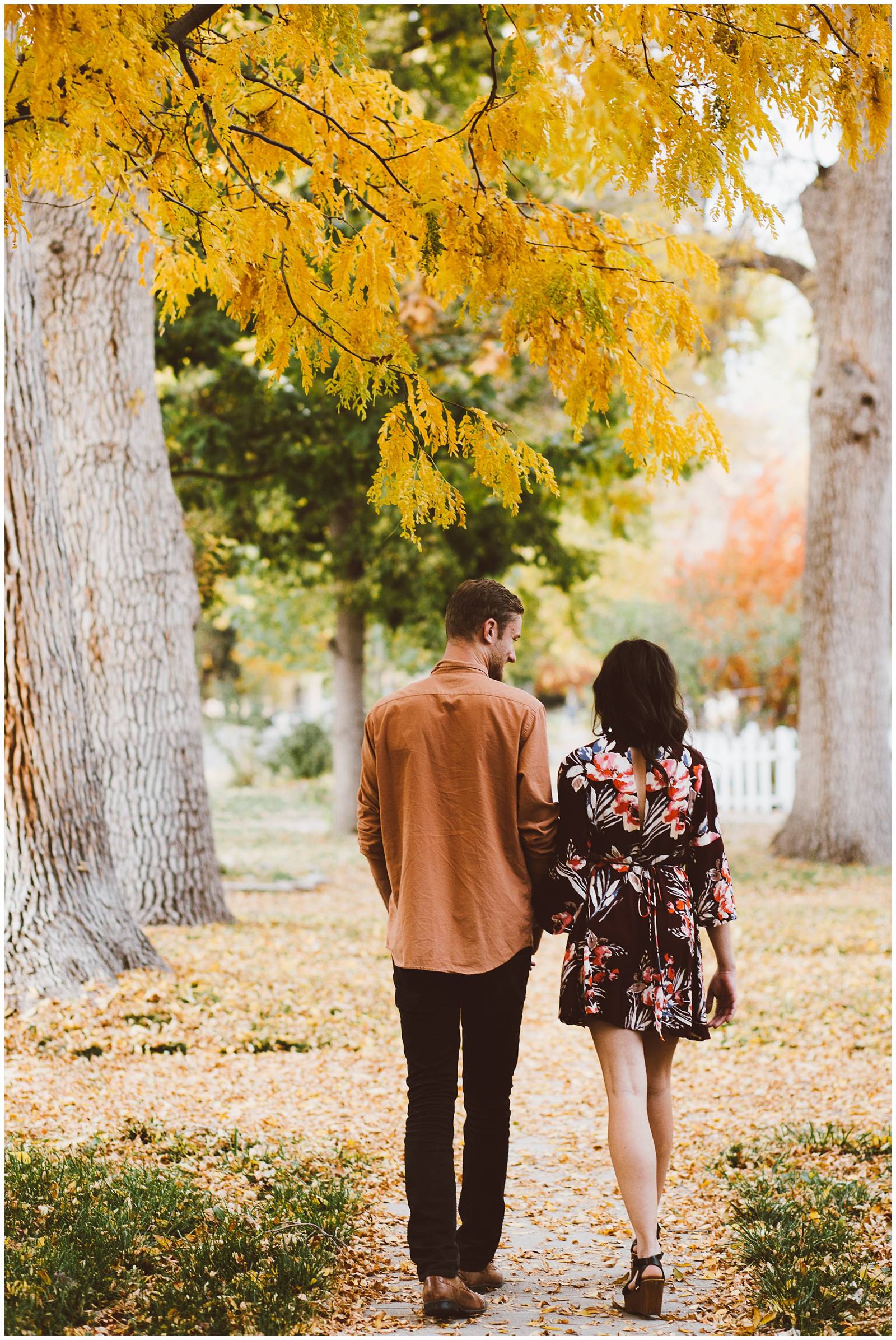 engaged couple walking through fall leaves | moody engagement photo inspiration