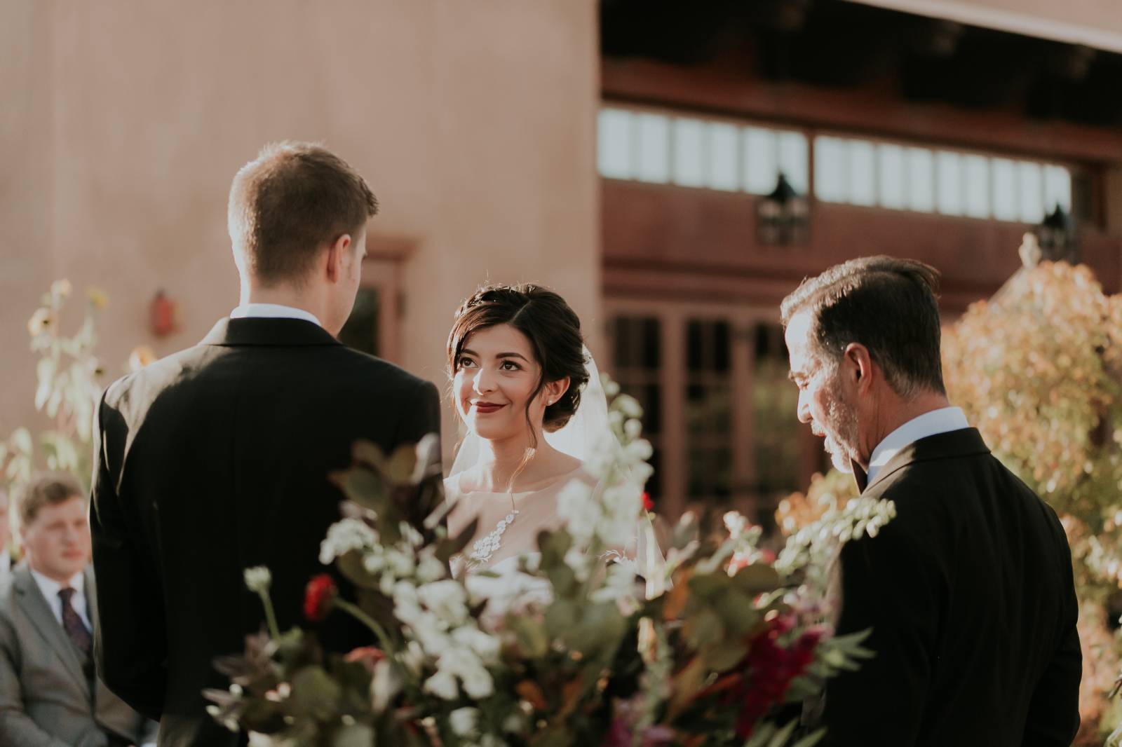 bride smiling at wedding ceremony | hair and makeup by Genica Lee