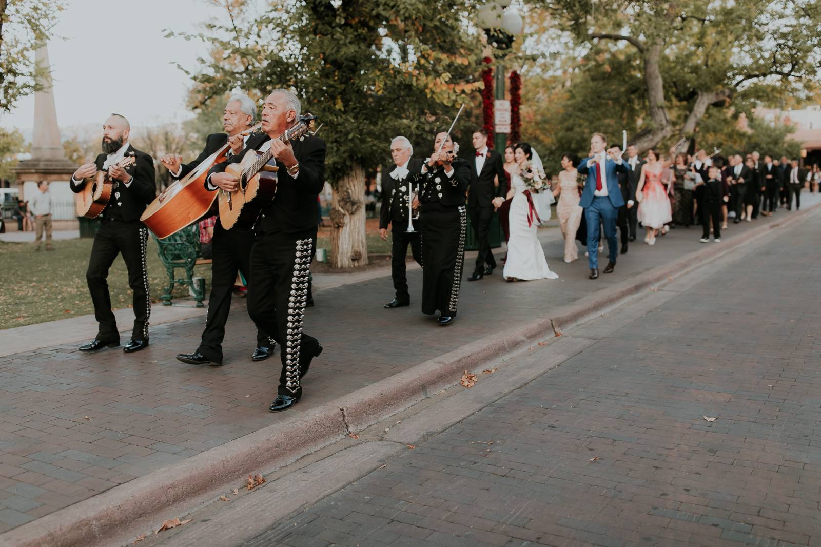 mariachi band leading bride groom and wedding guests around the block