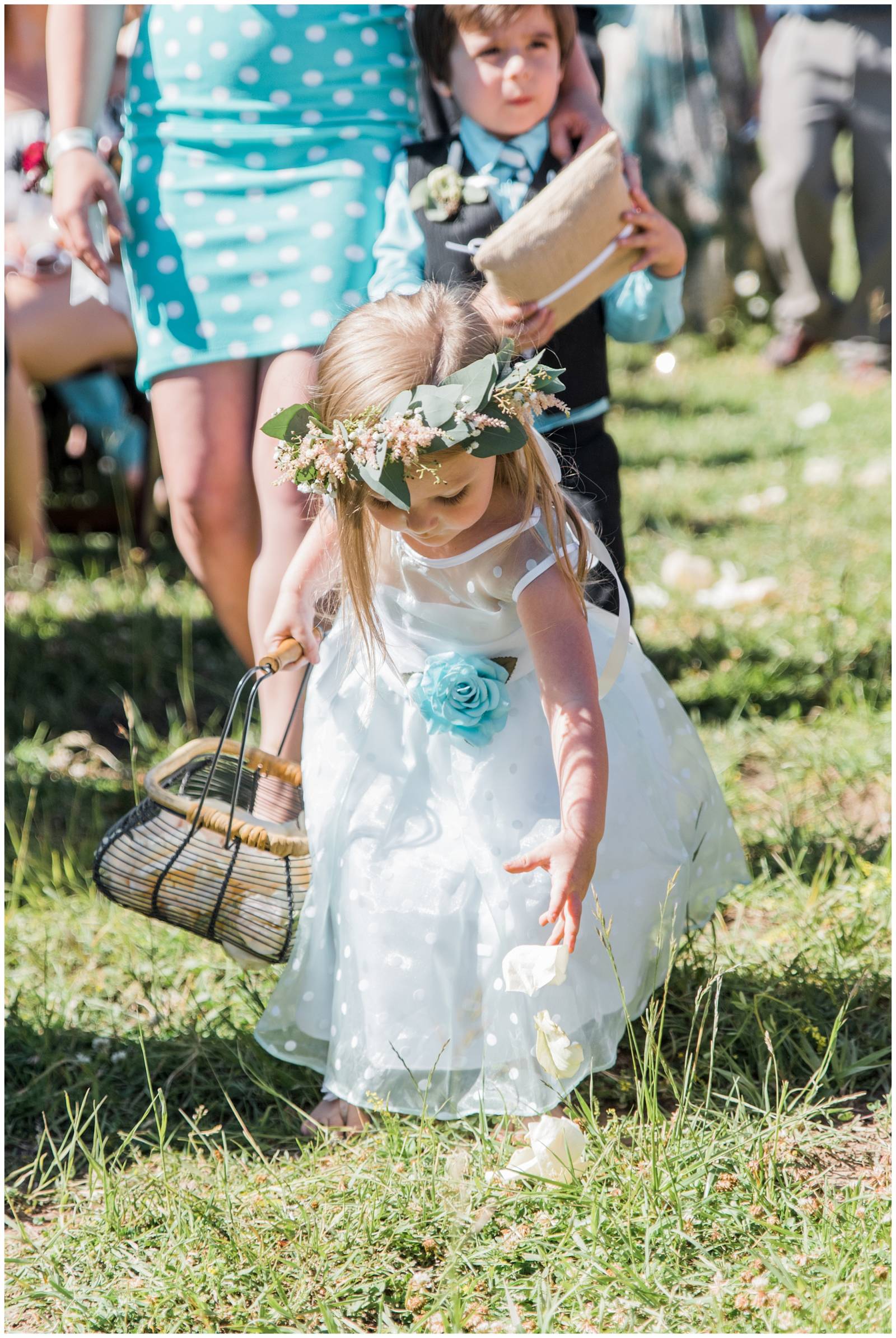 flower girl dropping flowers and wearing a blue flower