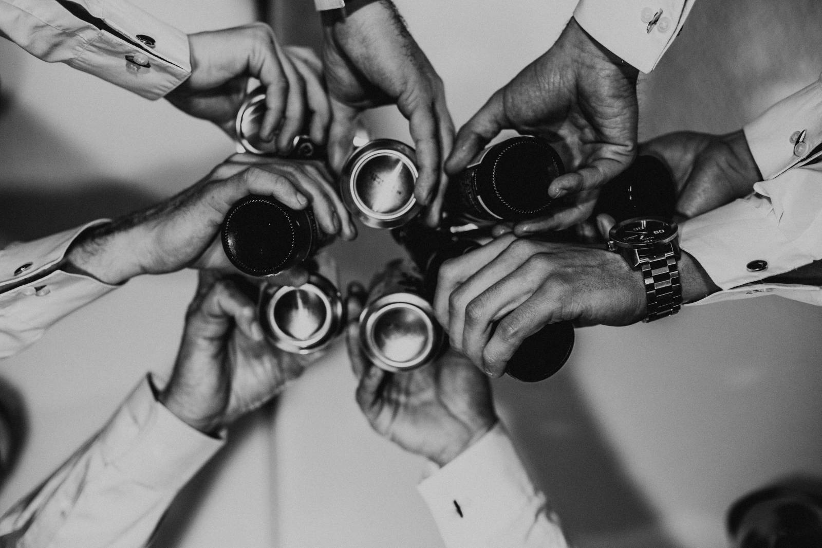 groom and groomsmen doing a cheers with their drinks