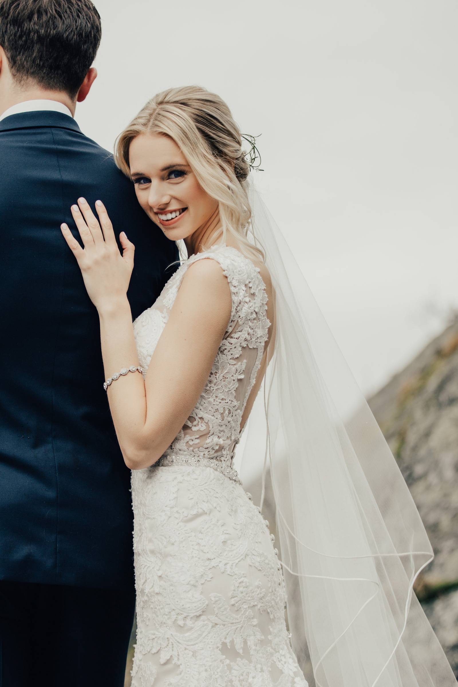 bride in lace wedding gown leaning against back of groom | Grouse Mountain wedding