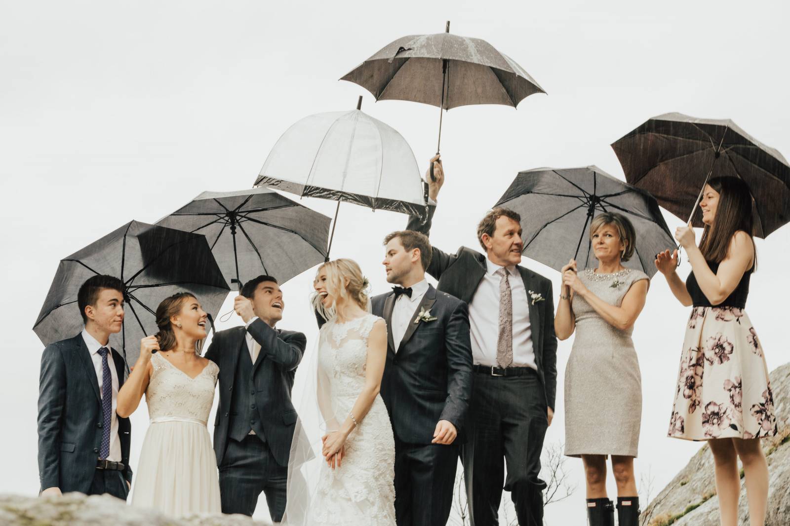 bride and groom's family with bride and groom wearing hunter boots and holding umbrellas at Grouse M