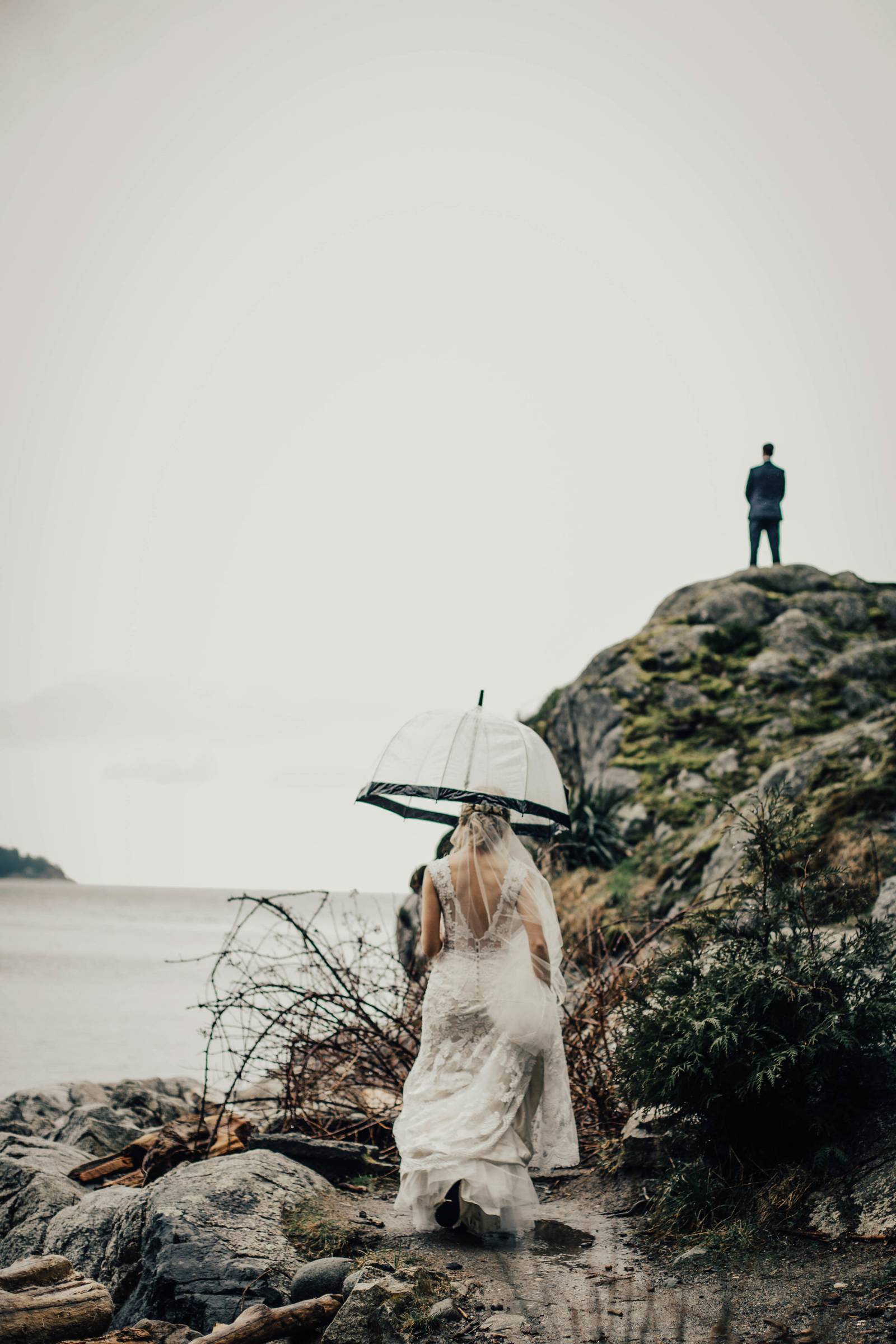 bride walking under umbrella up Grouse Mountain to groom for first look