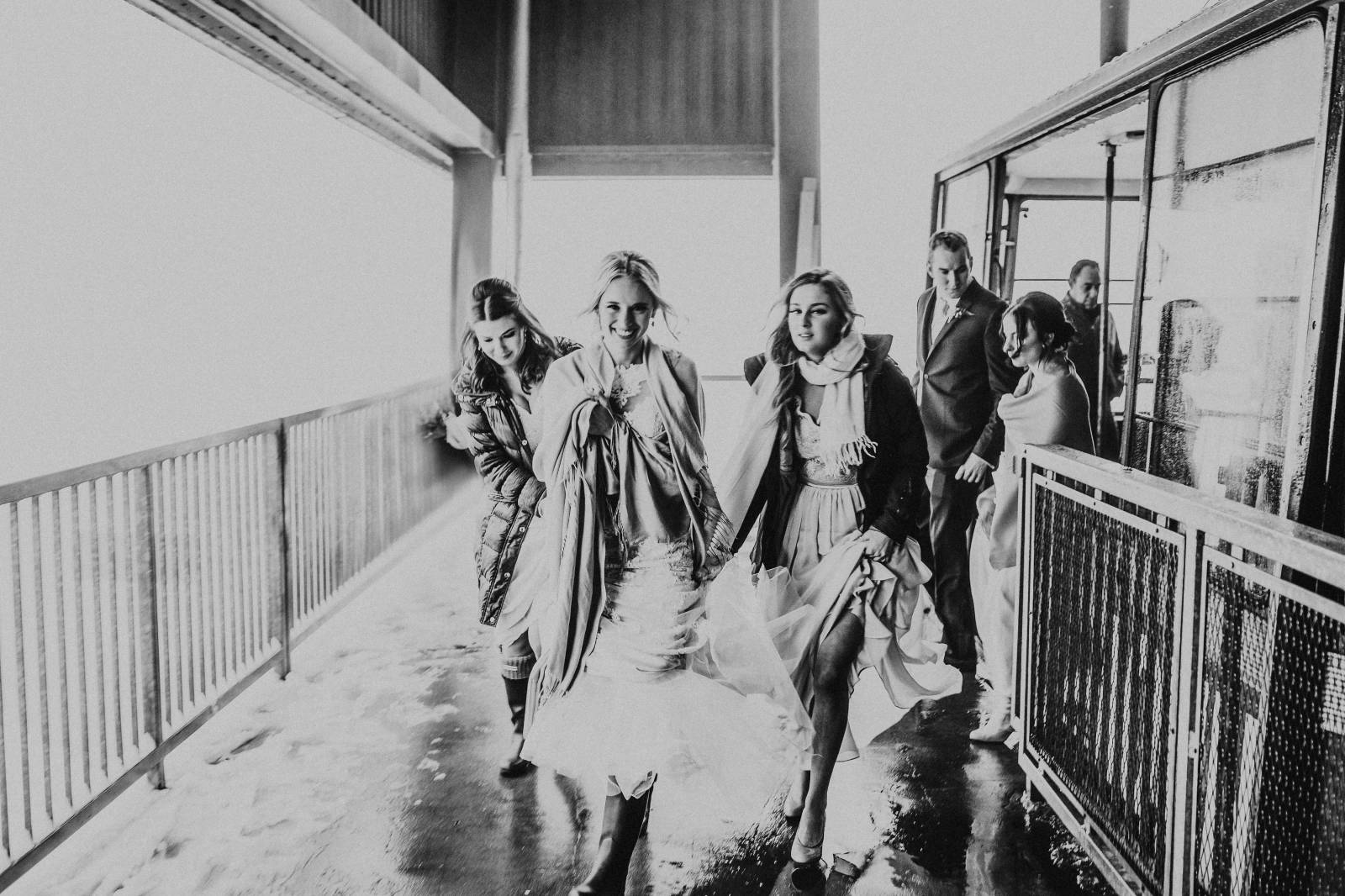 bride running with bridesmaids under blankets