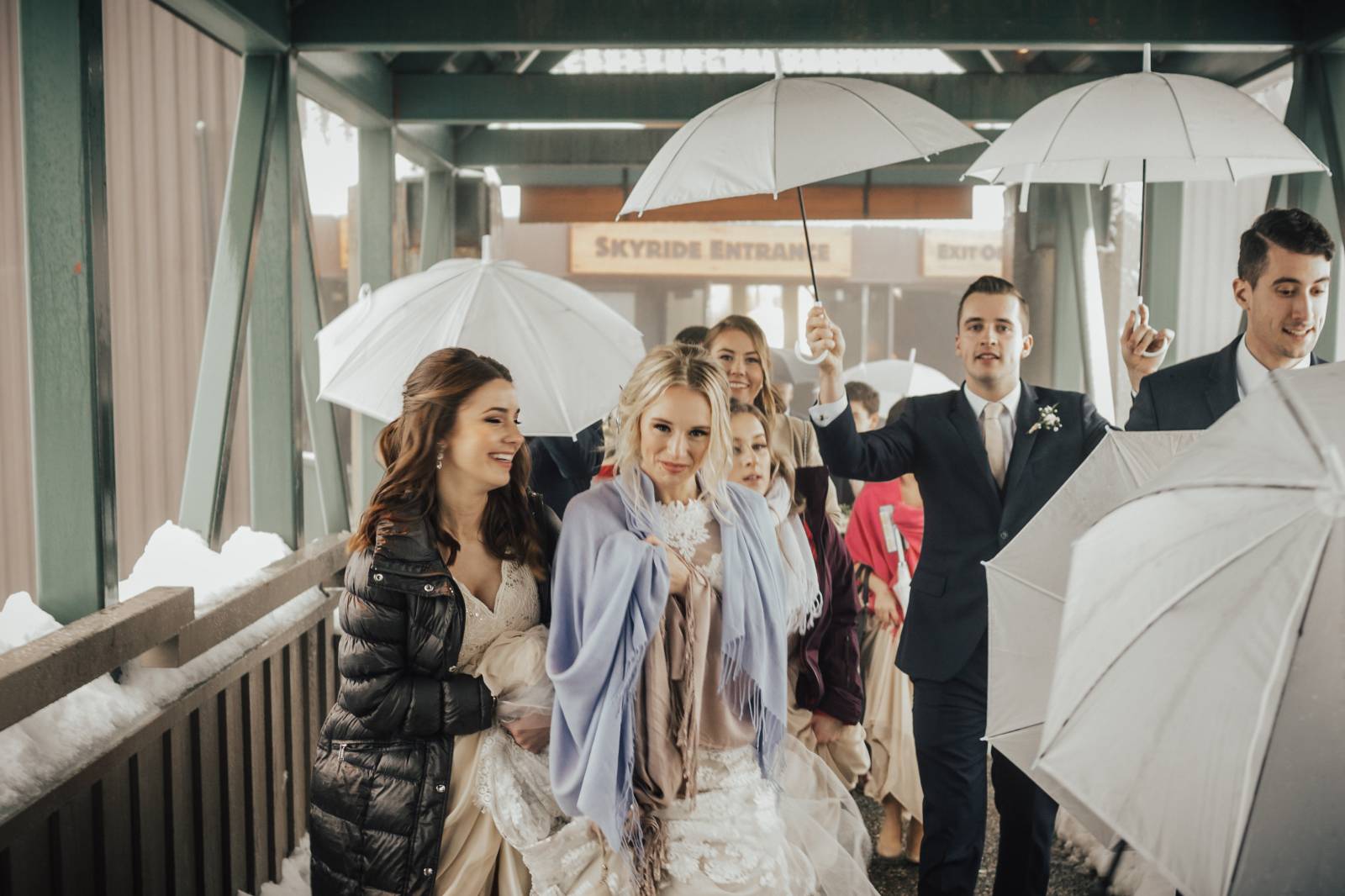 bride and bridesmaids under coats and blankets | Grouse Mountain Canadian wedding planned by Umbrell