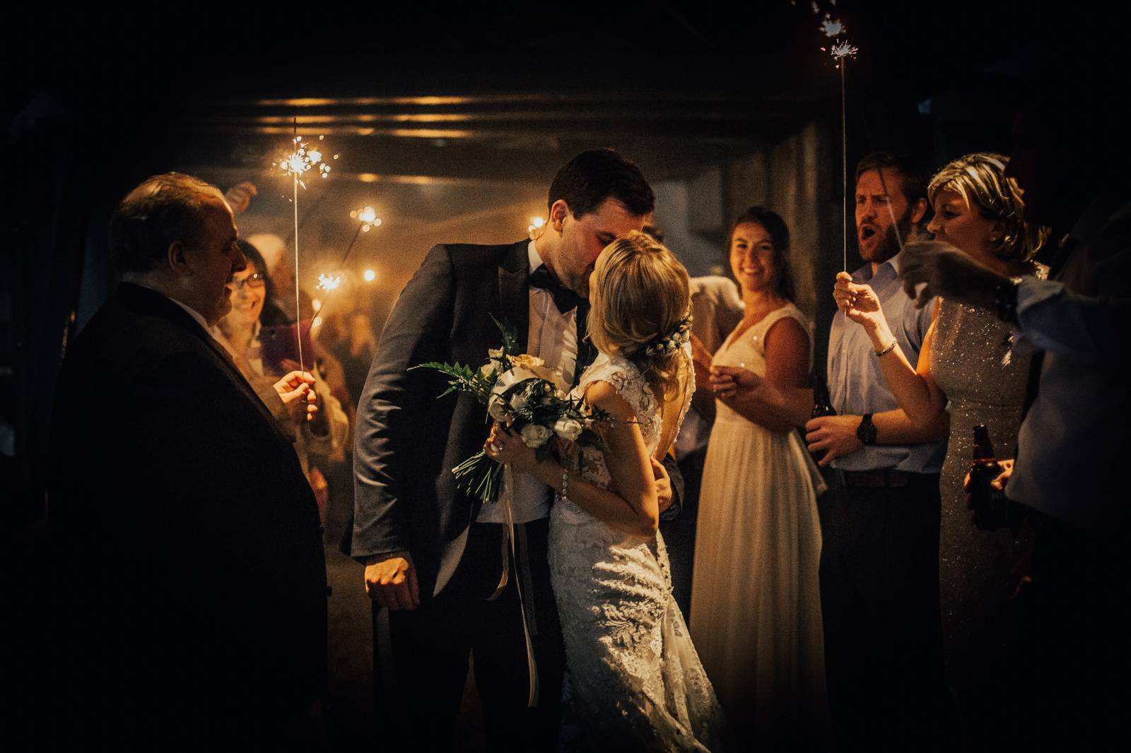 bride and groom kissing under the sparklers of the wedding guests