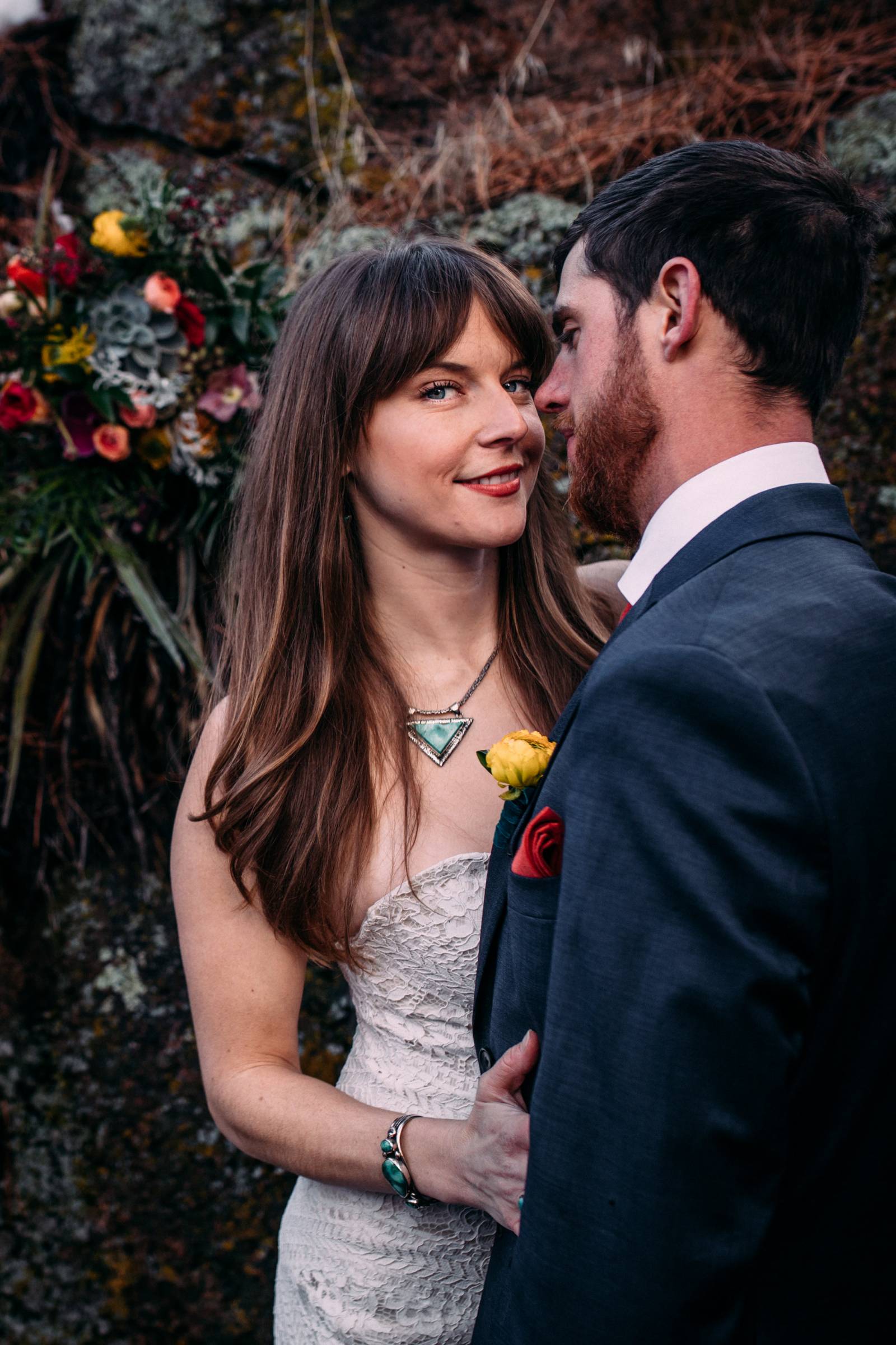bride with unique wedding necklace holding onto groom