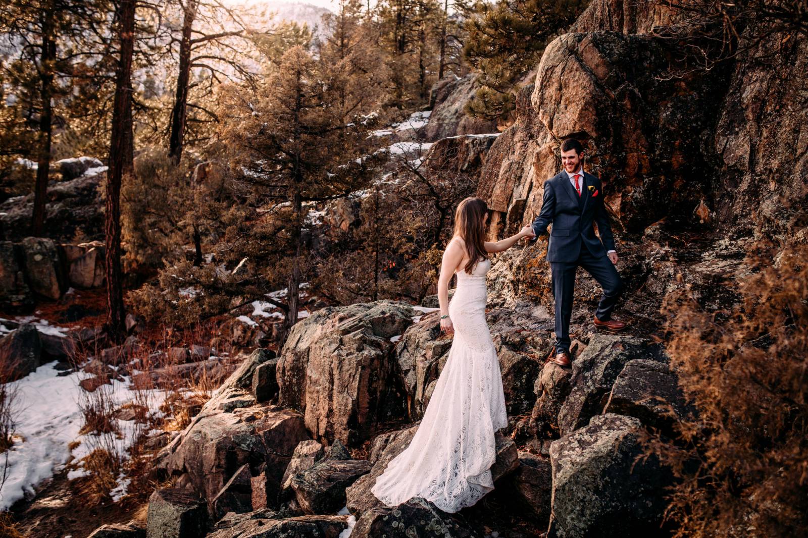 groom leading bride in stunning wedding gown up rocks in Emerald Isle Colorado