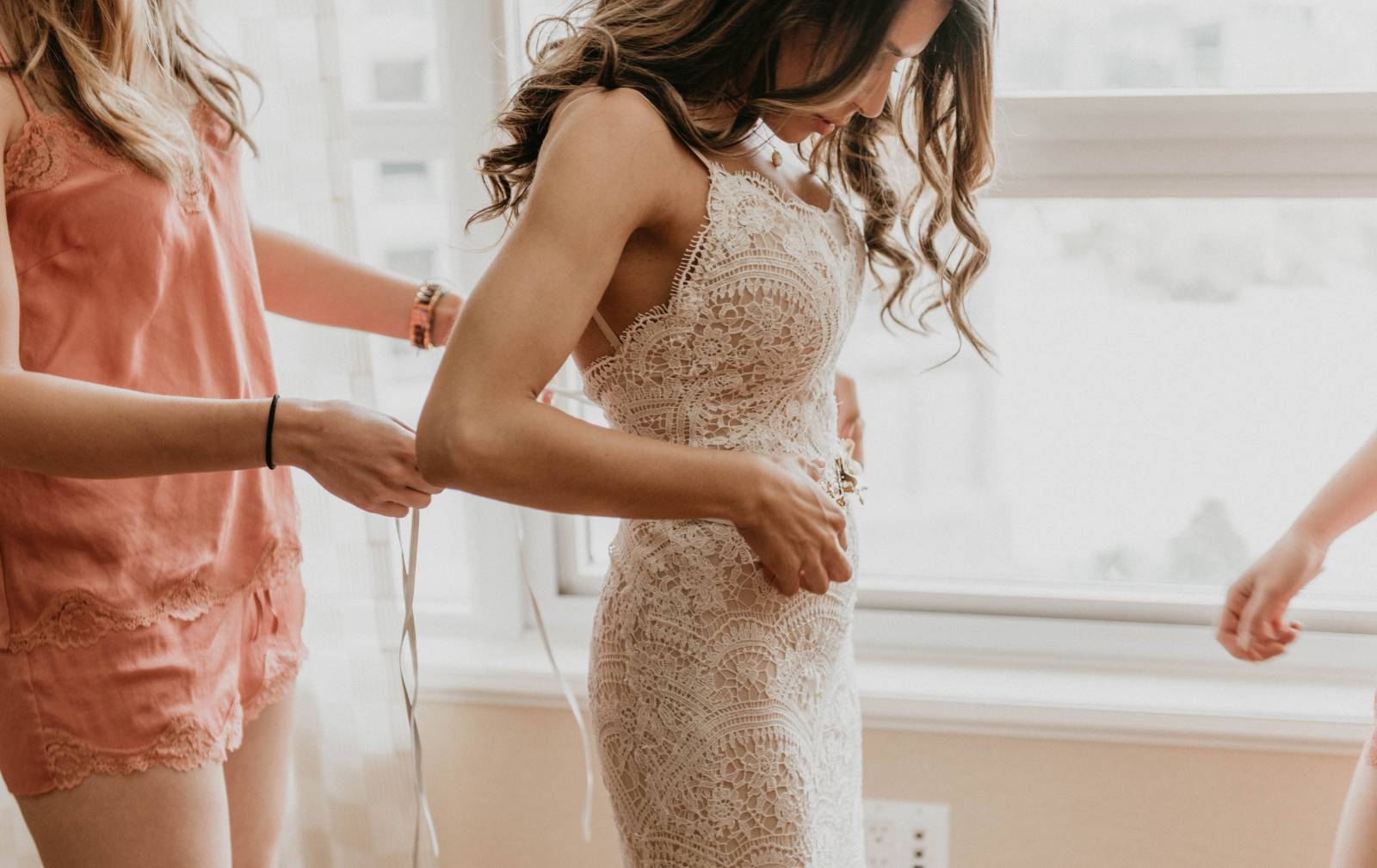 bridesmaid lacing up bride in her lace vintage wedding dress
