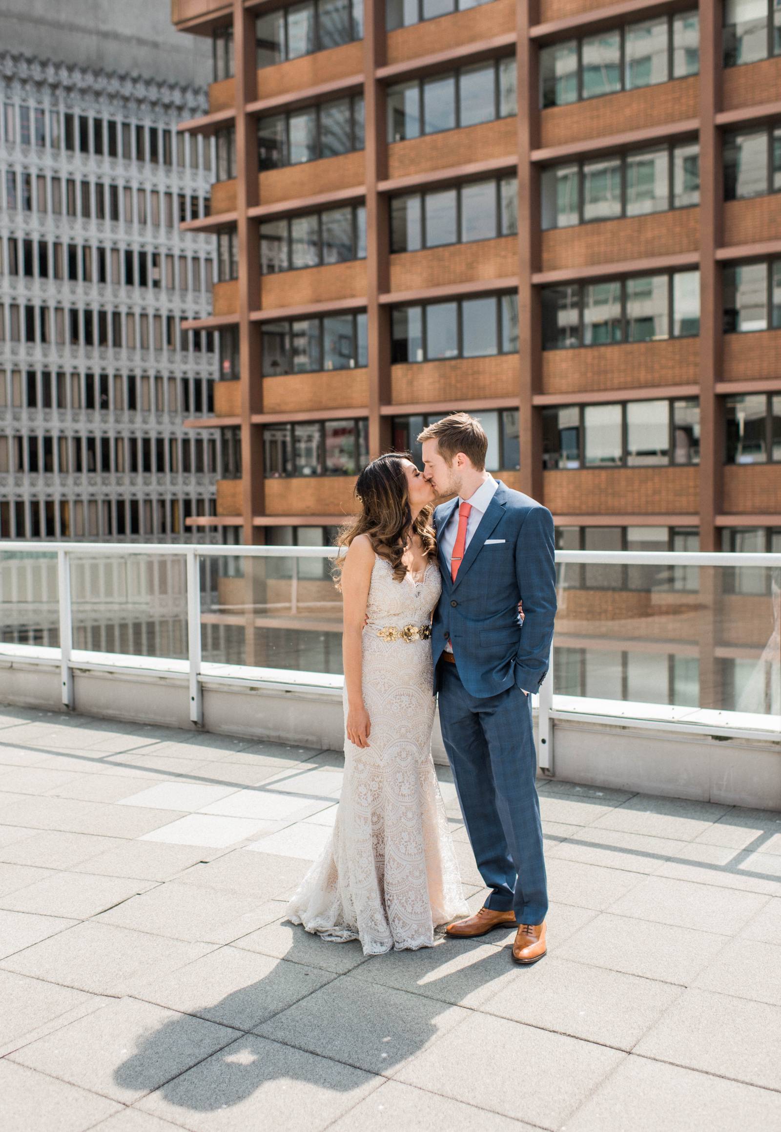 bride and groom kissing on top of city high rise