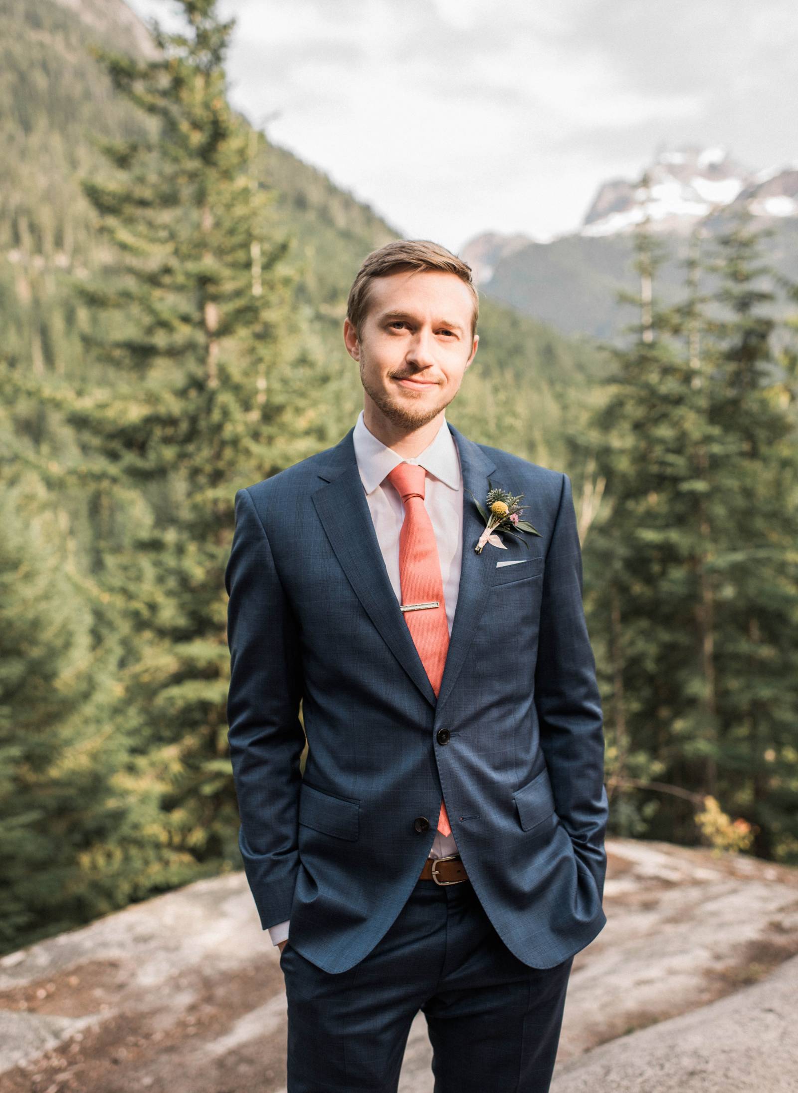 groom in coral tie and navy suit | groom style on mountain top