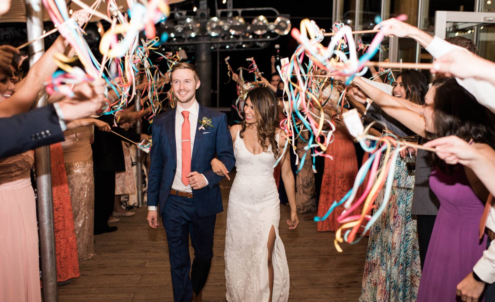 bride and groom leaving wedding reception under confetti