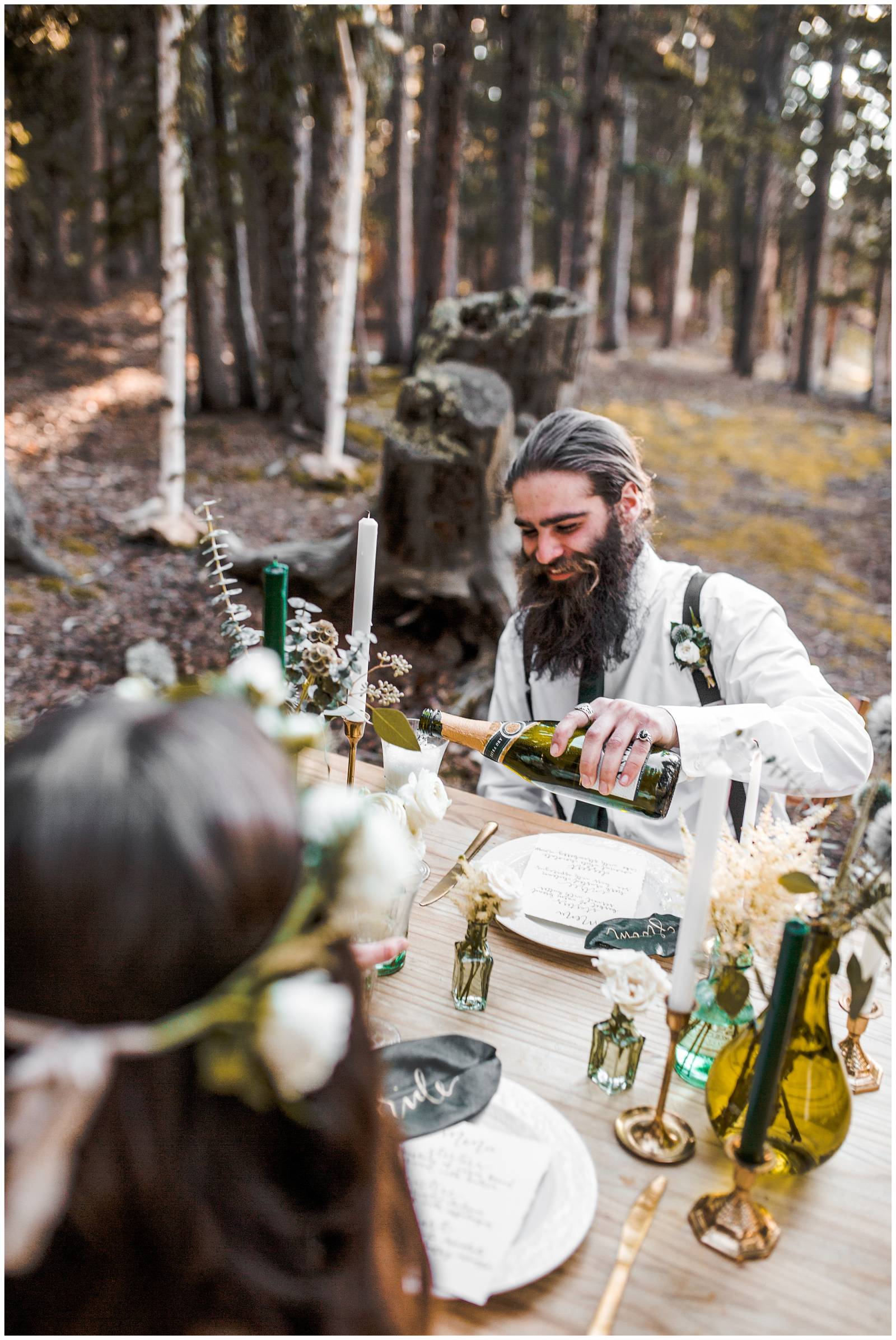 groom pouring champagne at elopement reception in mountains