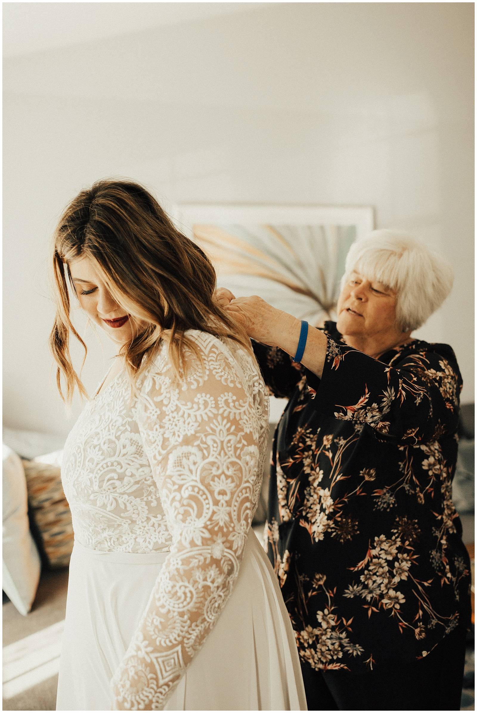 grandma buttoning up bride's lace wedding dress made by Natalie Wynn Design