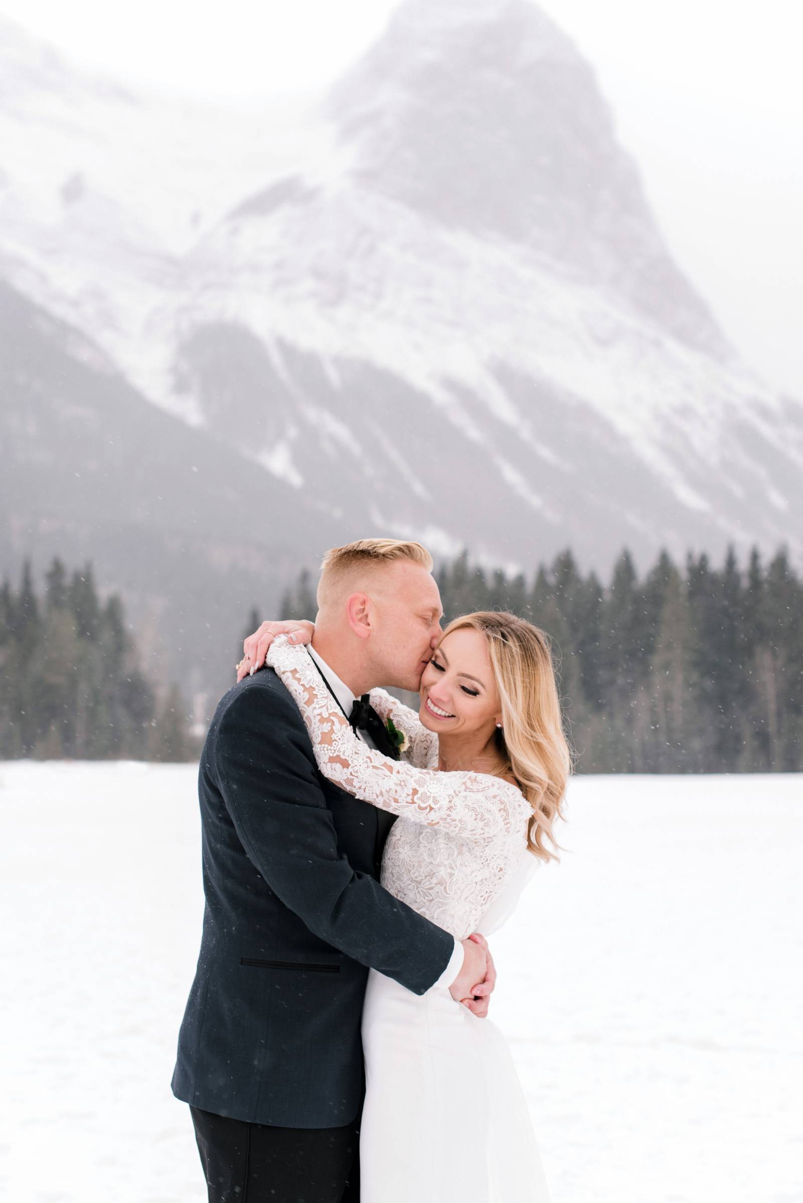 groom kissing the bride on the cheek | Canmore winter wedding inspiration