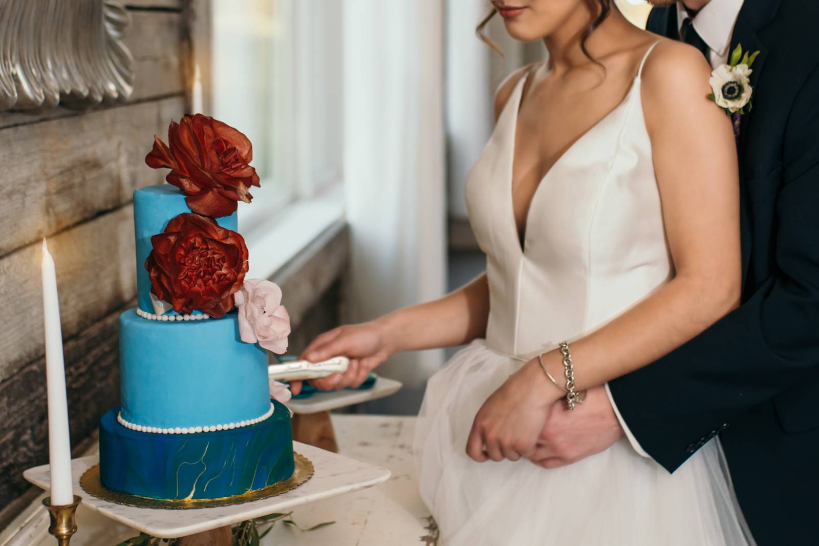 bride cutting blue wedding cake captured by Honeybee Weddings | blue and pink jewel toned wedding in