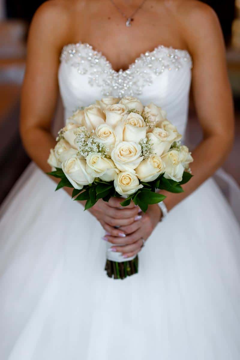 bride holding white rose and baby's breathe bouquet
