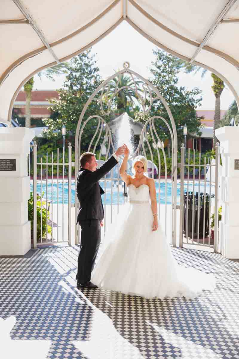 groom twirling bride in front of pool gate