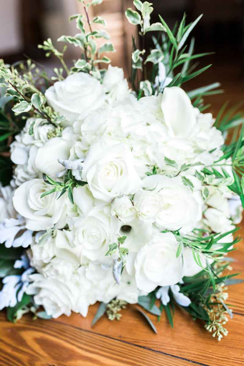 white bridal bouquet laying on wood table