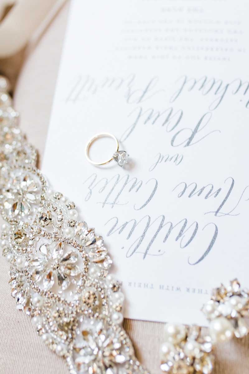 solitaire engagement ring laying on wedding invitation