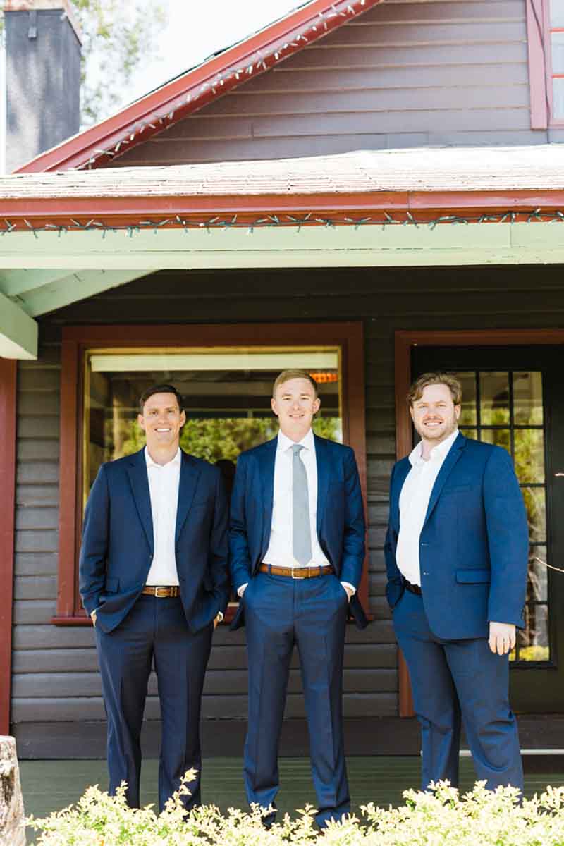 groom in navy suit under porch with groomsmen