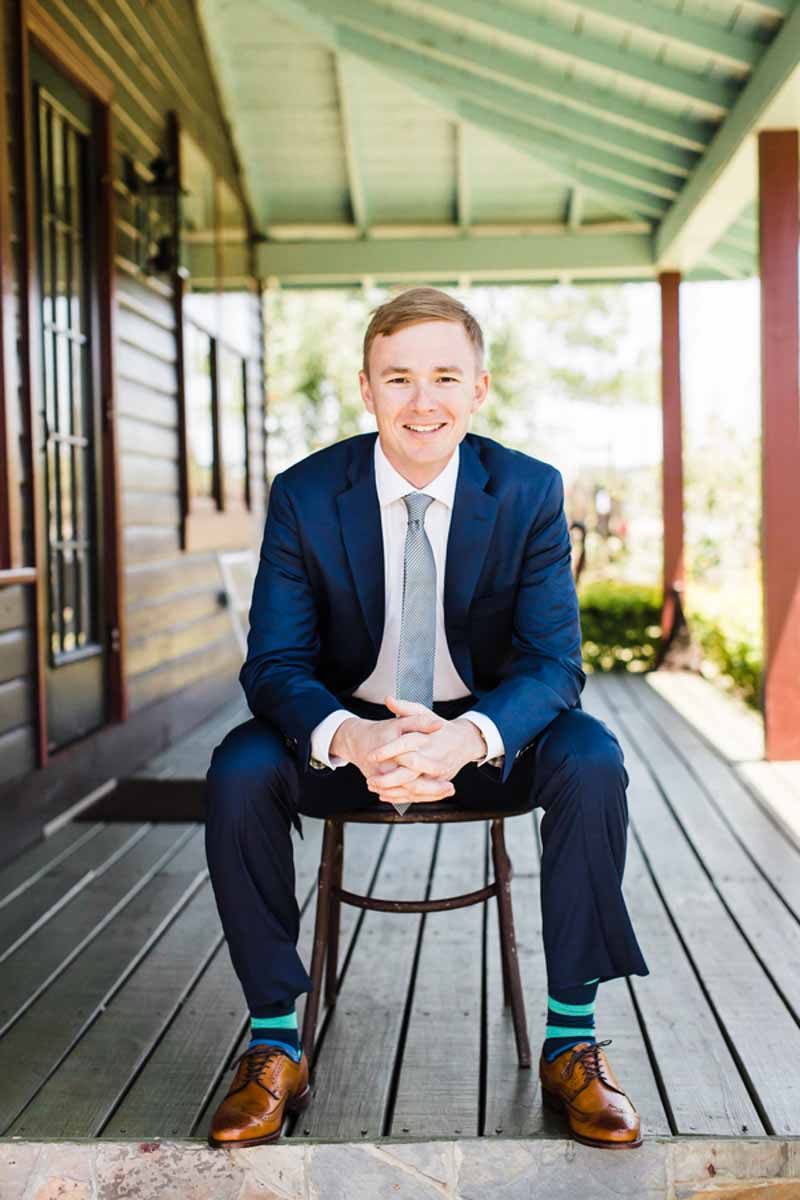groom sitting on stool under porch at the Acre Orlando