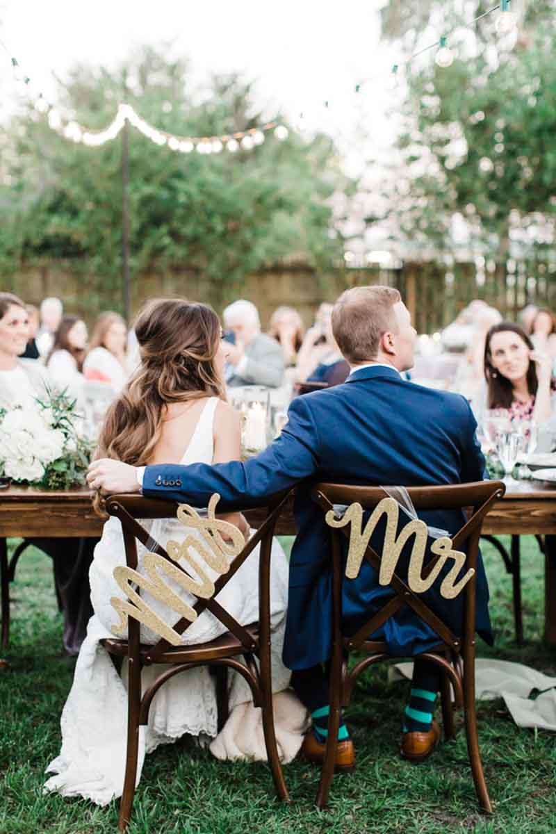 bride and groom sitting at sweetheart table listen to speech