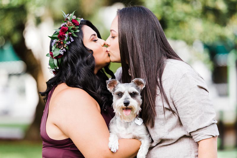 women kissing holding dog for engagement session