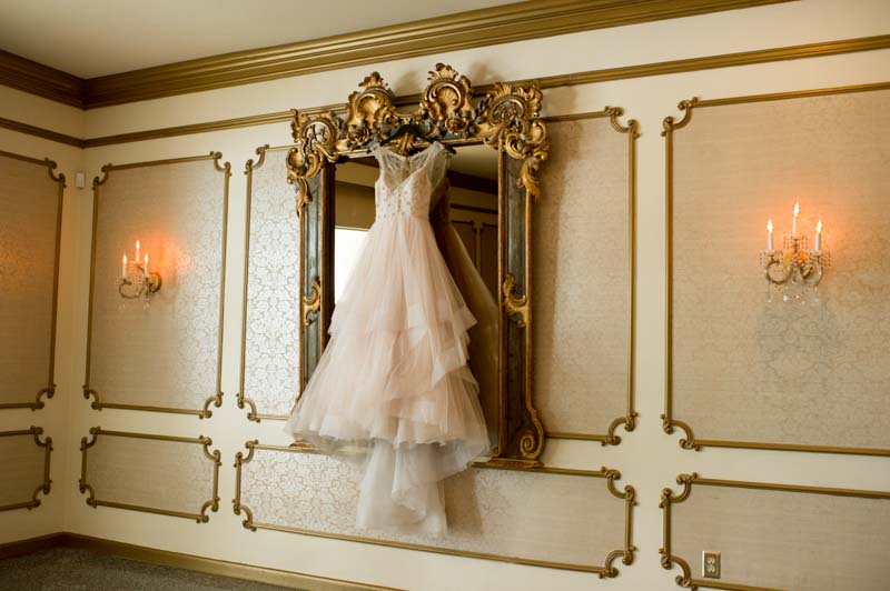 bridal gown hanging from ornate gold mirror