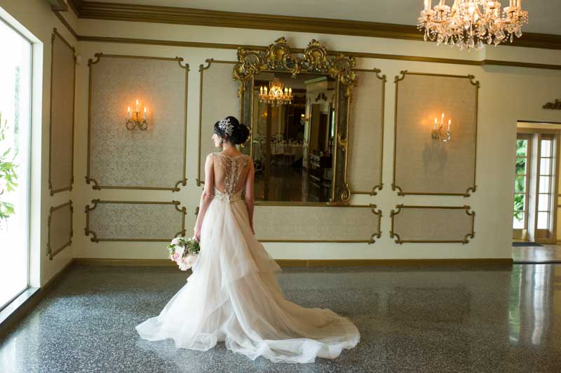 bride standing by window holding a bouquet