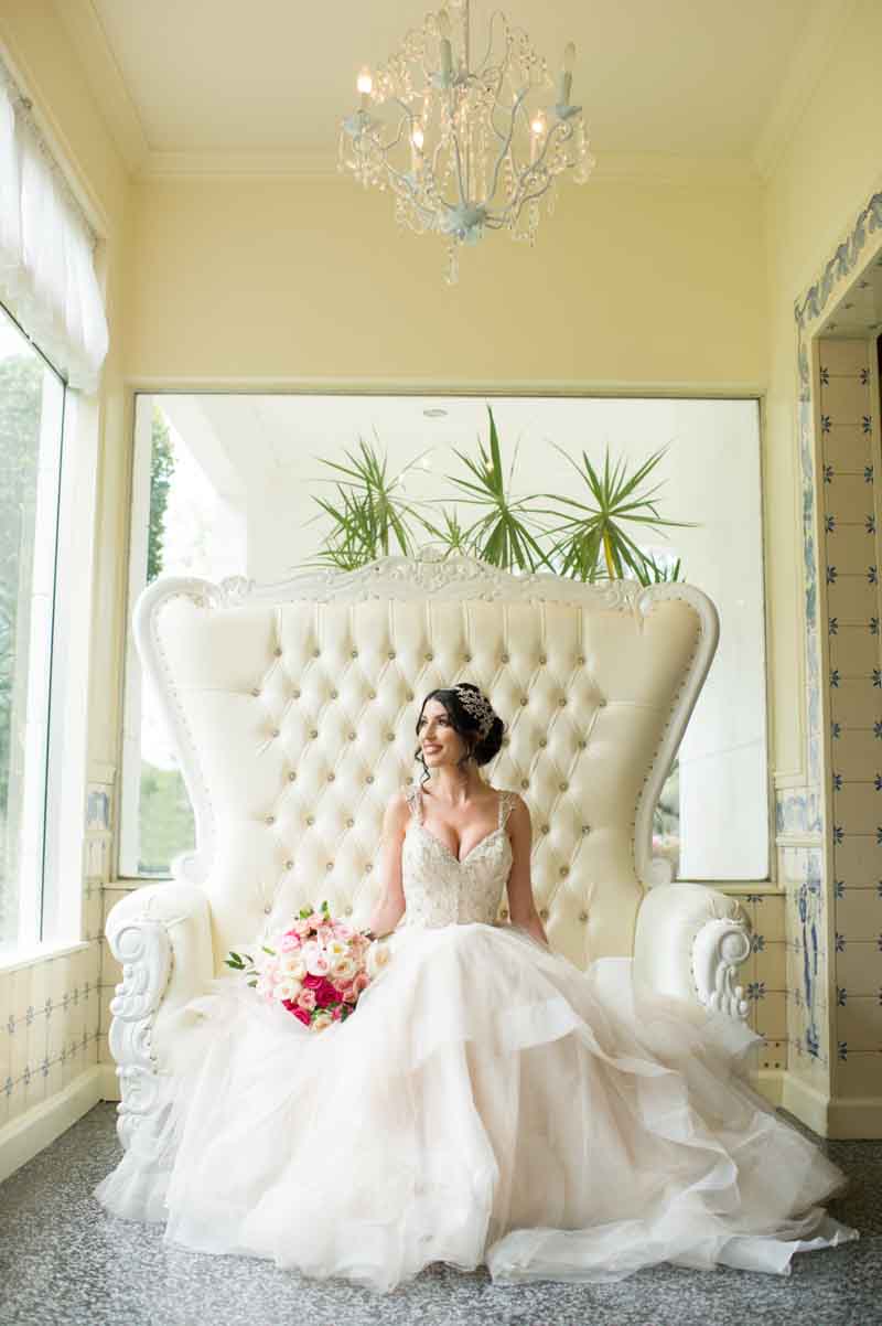bride sitting on high back white love seat