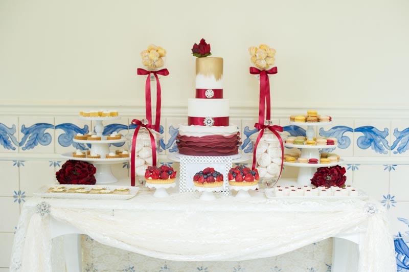 red and gold wedding cake on dessert table