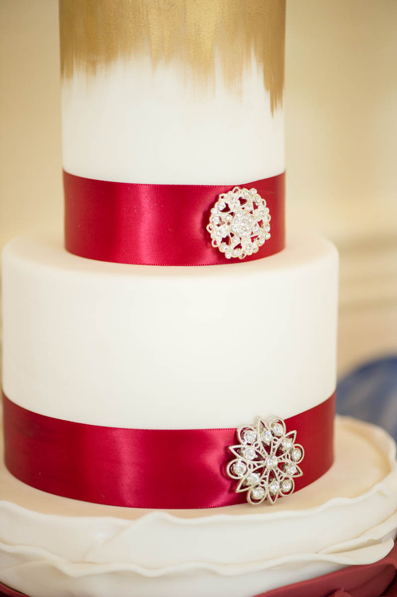 red ribbon with brooch on white wedding cake