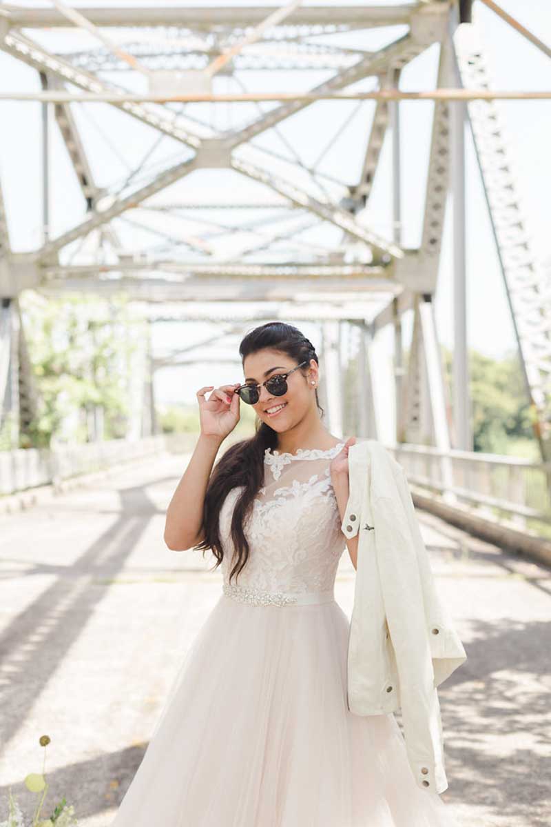 bride holding jacket over shoulder and tipping sunglasses