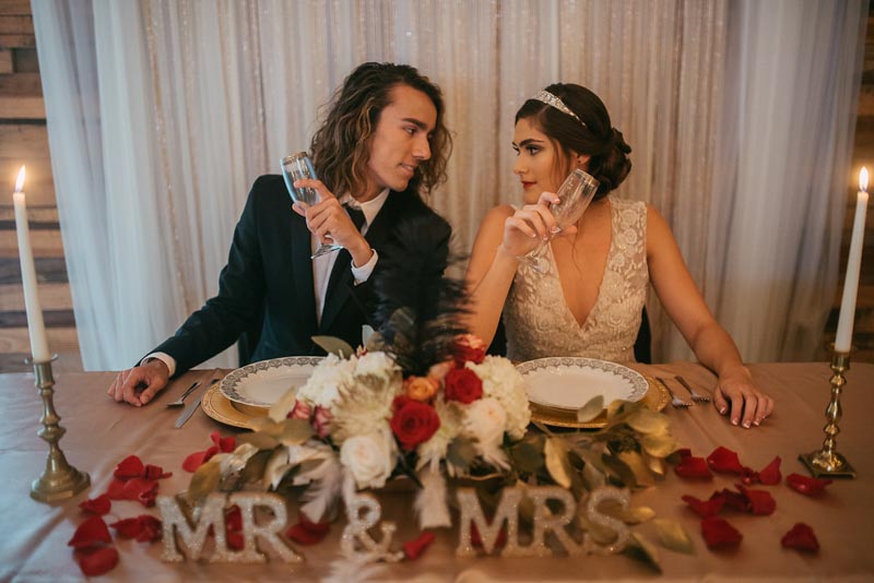 couple sitting at sweetheart table holding champagne glasses