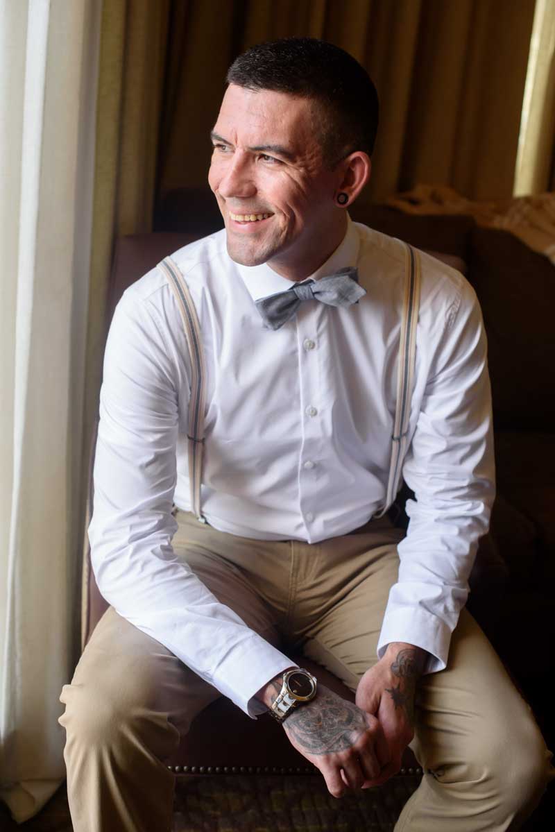 groom with blue bow tie looking out window