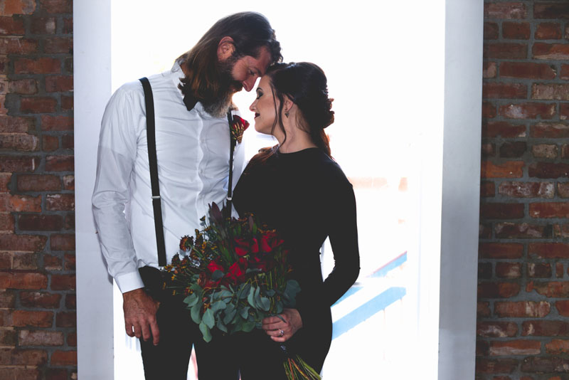 bride leaning forehead on groom while holding bouquet