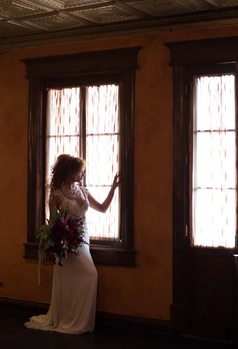 bride holding bouquet looking out window